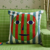 Decorative pillow with a face design on a green couch